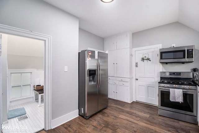 kitchen featuring vaulted ceiling, stainless steel appliances, dark wood-type flooring, and white cabinets