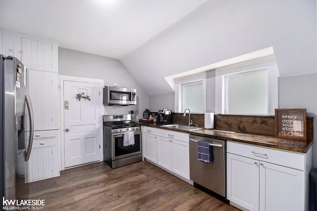 kitchen with dark hardwood / wood-style flooring, vaulted ceiling, sink, stainless steel appliances, and white cabinets