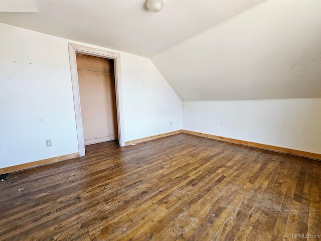 additional living space featuring vaulted ceiling and dark wood-type flooring