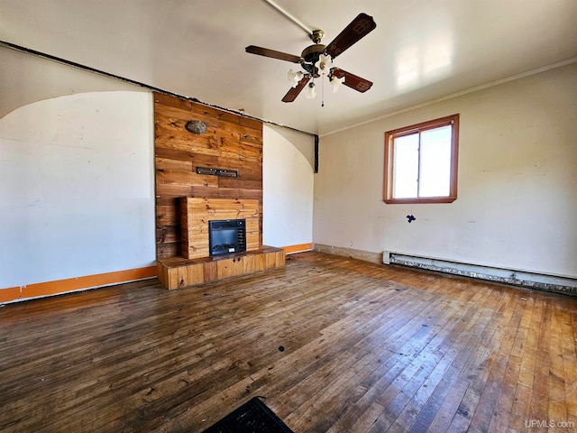 unfurnished living room featuring ceiling fan, wood-type flooring, wooden walls, a baseboard radiator, and a fireplace