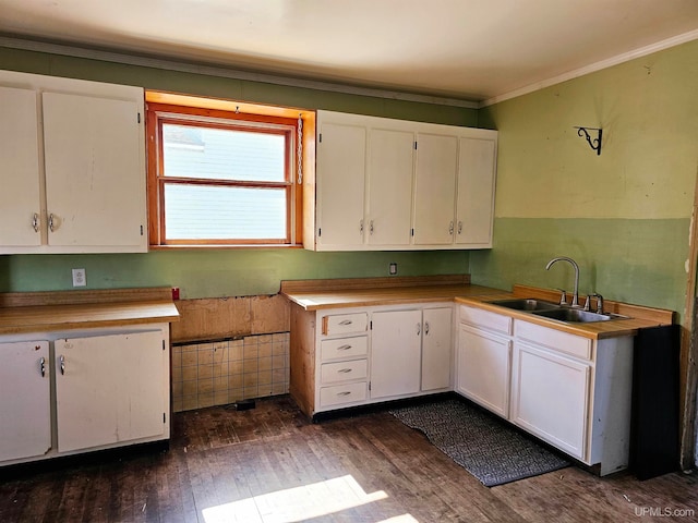 kitchen featuring white cabinetry, crown molding, dark wood-type flooring, and sink