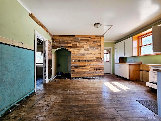 kitchen with white cabinets, dark hardwood / wood-style floors, wood walls, and crown molding