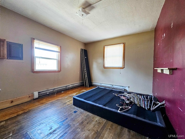 unfurnished bedroom with a baseboard radiator, wood-type flooring, and a textured ceiling