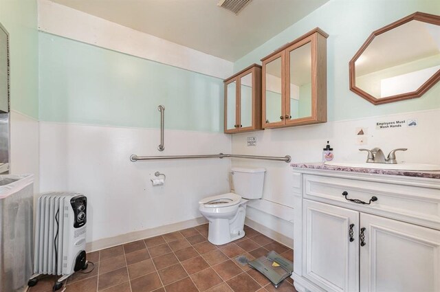 bathroom featuring vanity, heating unit, toilet, and tile patterned floors