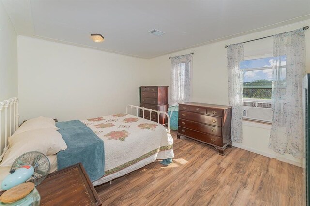 bedroom featuring light wood-type flooring and crown molding