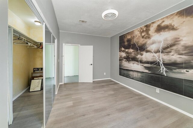 unfurnished bedroom with light hardwood / wood-style flooring, a closet, and a textured ceiling