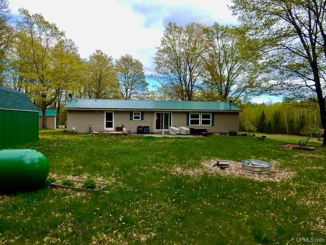 rear view of property with a shed, a yard, and a fire pit