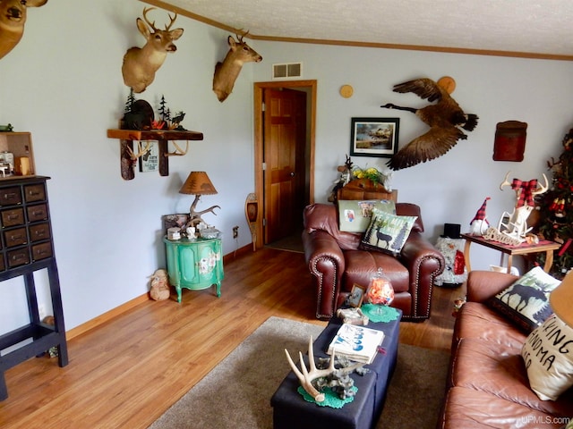 living room with ornamental molding, a textured ceiling, and hardwood / wood-style floors