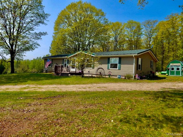 view of front of house with a front yard, a storage shed, and a deck