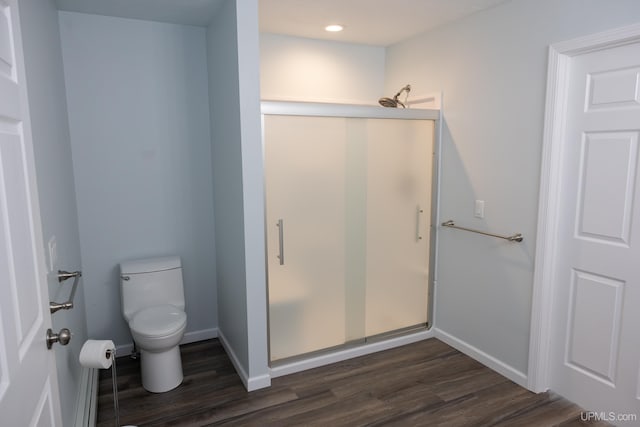 bathroom with wood-type flooring, toilet, and a shower with shower door