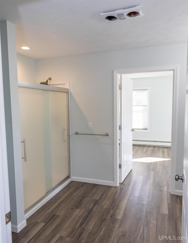 bathroom with a baseboard heating unit, a shower with door, hardwood / wood-style flooring, and a textured ceiling