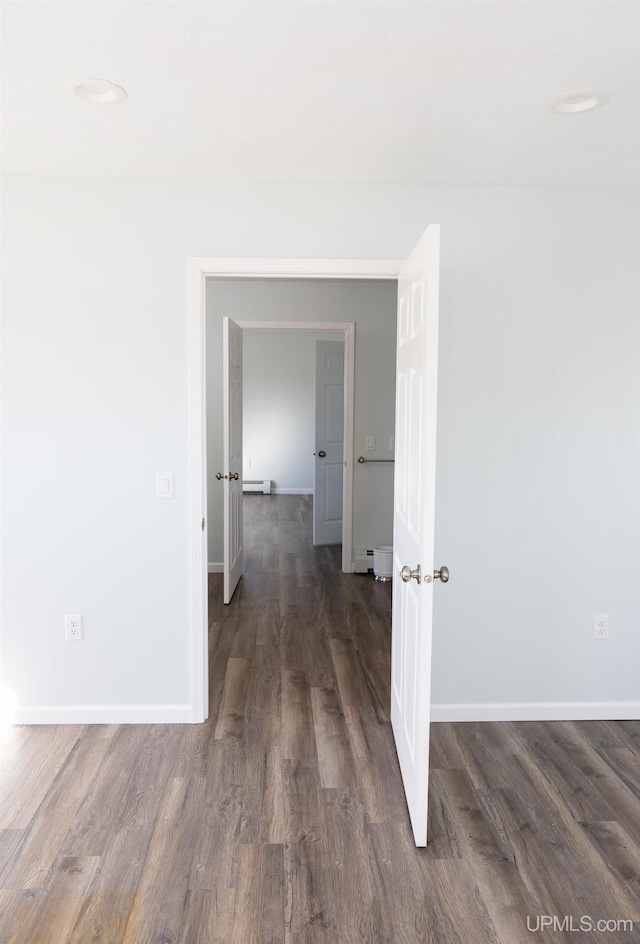 corridor with a baseboard radiator and dark hardwood / wood-style flooring