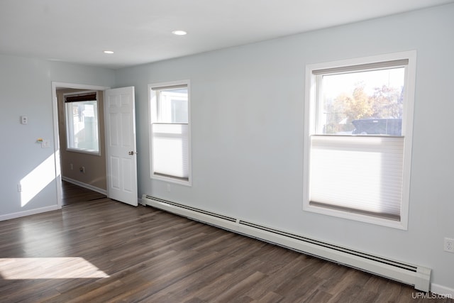 spare room with a baseboard heating unit and dark hardwood / wood-style floors