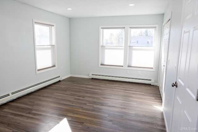 unfurnished room featuring dark hardwood / wood-style flooring, a baseboard heating unit, and a healthy amount of sunlight