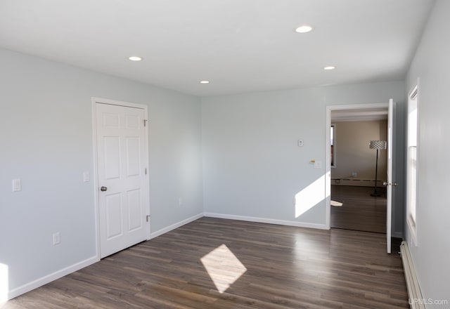 empty room with dark wood-type flooring and a baseboard radiator