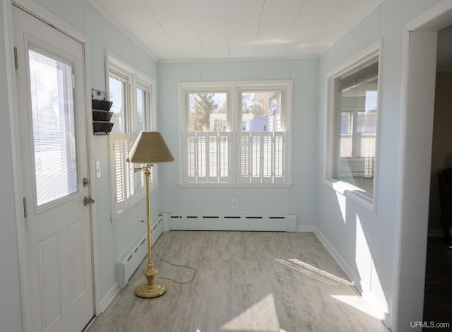 unfurnished sunroom featuring a baseboard heating unit and a wealth of natural light