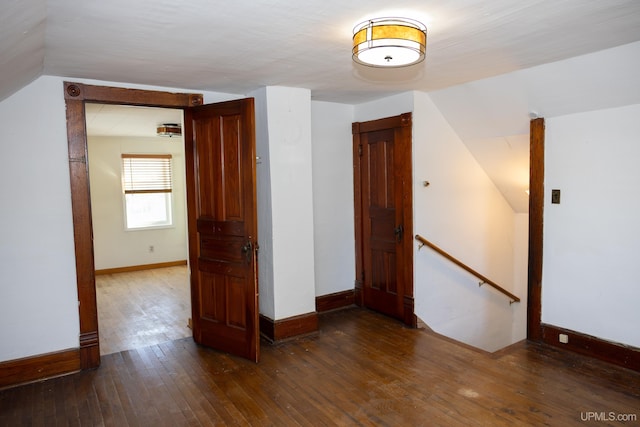 unfurnished room featuring lofted ceiling and dark hardwood / wood-style flooring