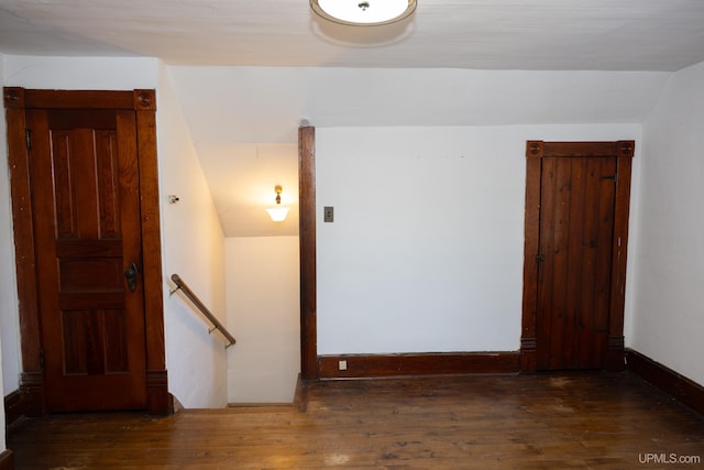 empty room with dark wood-type flooring and vaulted ceiling