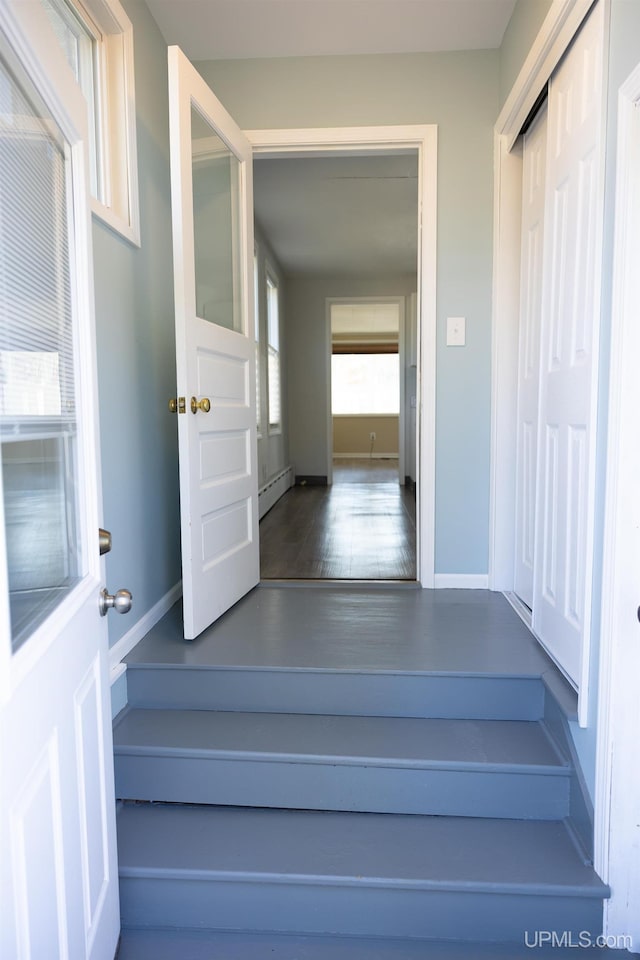 stairs featuring baseboard heating and hardwood / wood-style floors