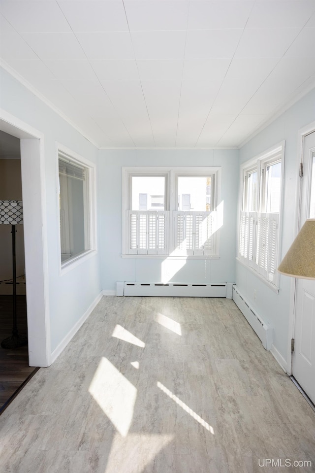 empty room with a baseboard radiator, a wealth of natural light, and light hardwood / wood-style floors