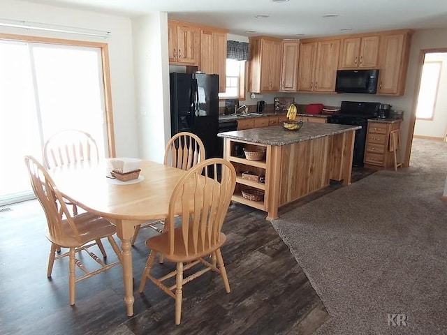 kitchen with black appliances, a kitchen island, sink, and dark wood-type flooring