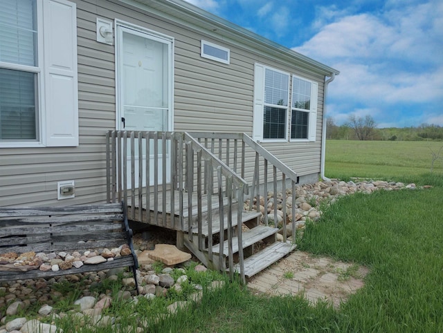 view of exterior entry with a lawn and a wooden deck