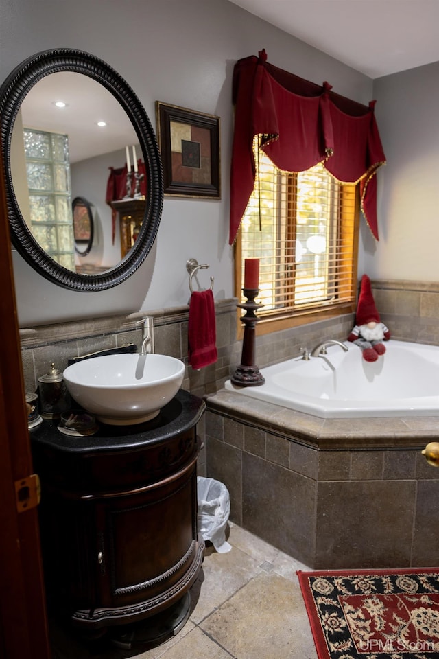 bathroom with tile patterned floors, tiled tub, and vanity