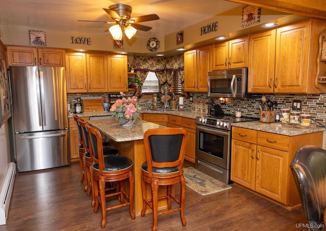 kitchen with stainless steel appliances, light stone counters, a center island, and dark hardwood / wood-style flooring