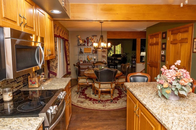 kitchen featuring a chandelier, dark hardwood / wood-style floors, appliances with stainless steel finishes, decorative light fixtures, and light stone countertops