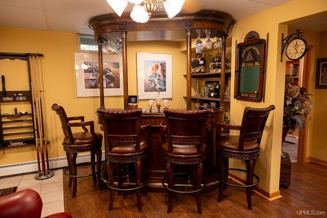 bar featuring a baseboard radiator and hardwood / wood-style floors