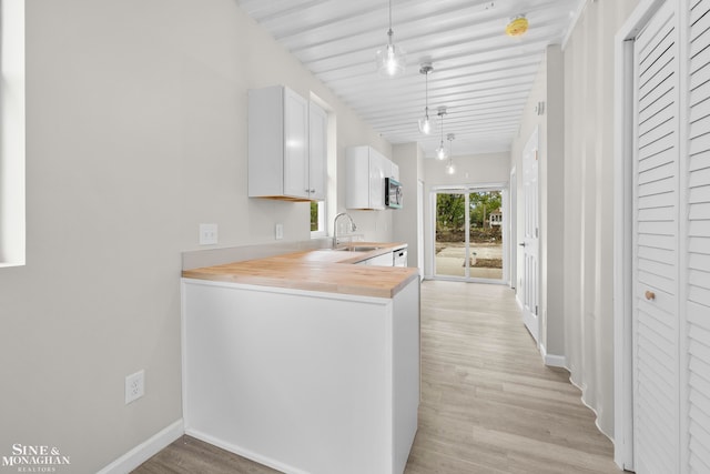 kitchen with butcher block countertops, light hardwood / wood-style floors, hanging light fixtures, and rail lighting