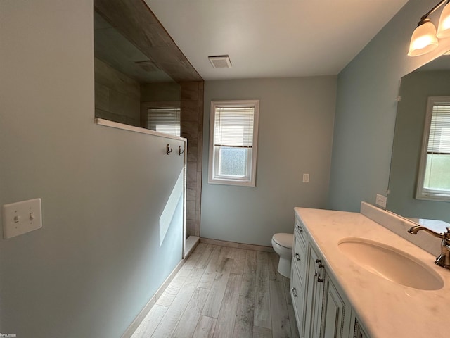 bathroom with plenty of natural light, hardwood / wood-style floors, vanity, and toilet