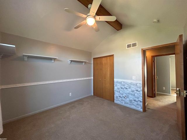 unfurnished bedroom with a closet, light colored carpet, vaulted ceiling with beams, and ceiling fan