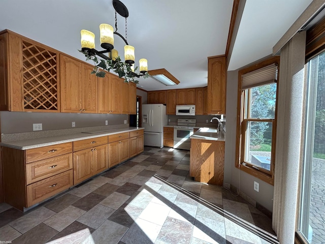 kitchen featuring sink, white appliances, decorative light fixtures, and a chandelier