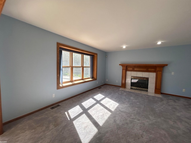 unfurnished living room featuring a tiled fireplace and carpet