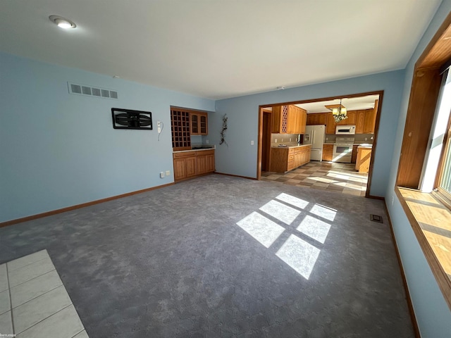 unfurnished living room with light colored carpet and a notable chandelier