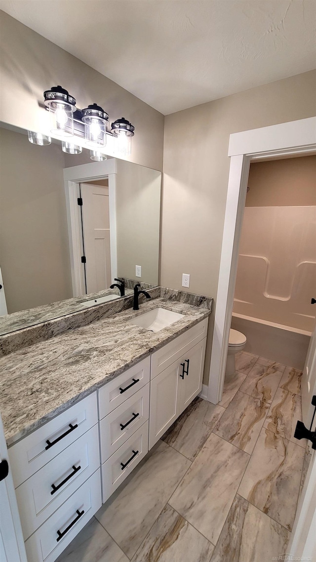 bathroom featuring vanity, a washtub, and toilet