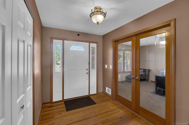 foyer entrance featuring light wood-type flooring, a healthy amount of sunlight, and french doors