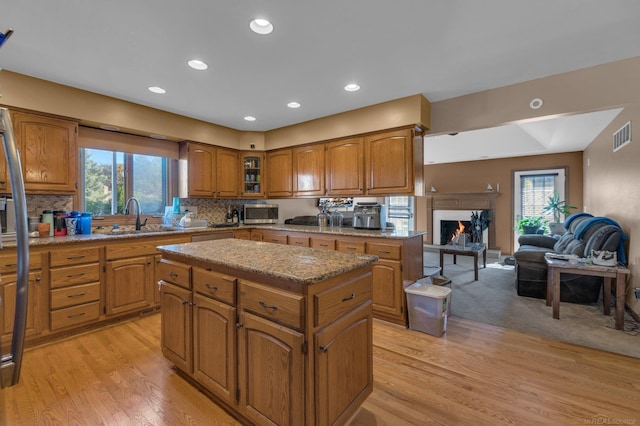 kitchen with light wood-type flooring, plenty of natural light, sink, and a center island