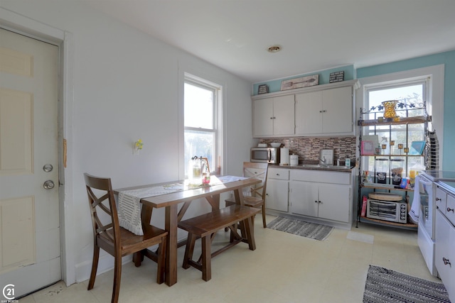 kitchen with white cabinets, light tile patterned flooring, backsplash, and a healthy amount of sunlight