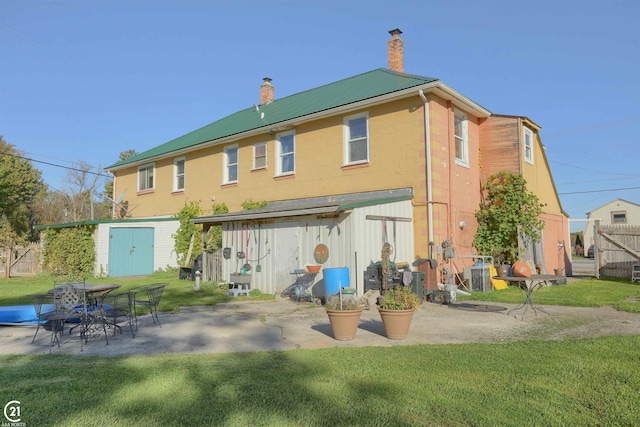 back of house with cooling unit, a yard, and a storage unit