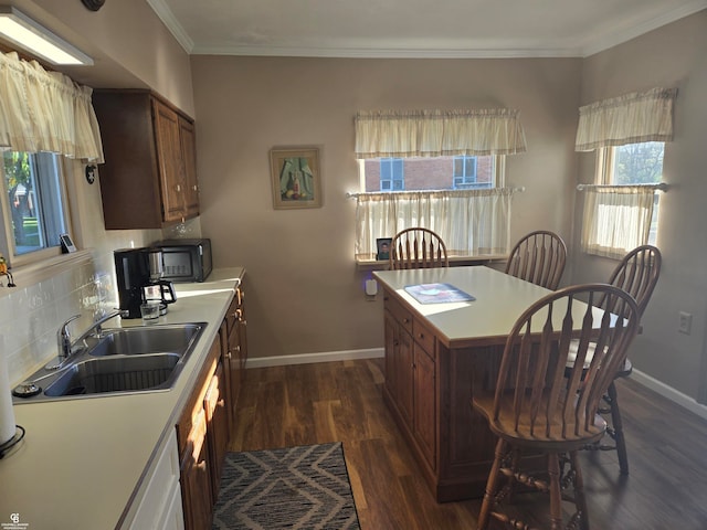 kitchen featuring dark hardwood / wood-style floors, crown molding, backsplash, and sink