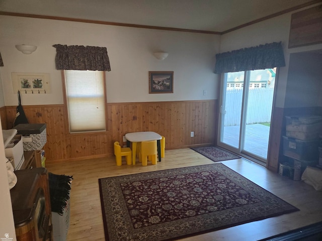 living room with ornamental molding, wooden walls, and wood-type flooring