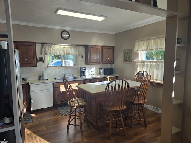 kitchen featuring sink, dark wood-type flooring, fridge, crown molding, and a kitchen bar