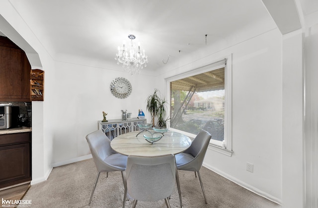 dining area with light colored carpet and an inviting chandelier