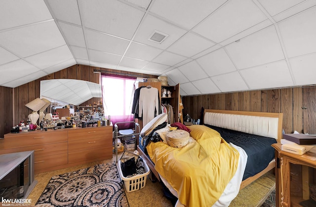 bedroom featuring lofted ceiling, wooden walls, and carpet flooring