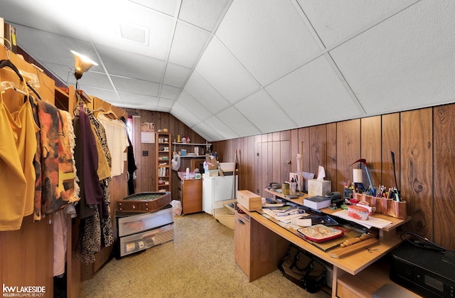 carpeted office with lofted ceiling and wooden walls