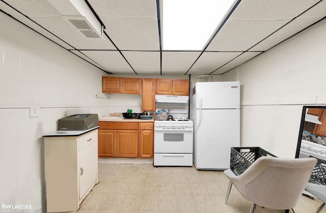 kitchen featuring a paneled ceiling, white appliances, and sink