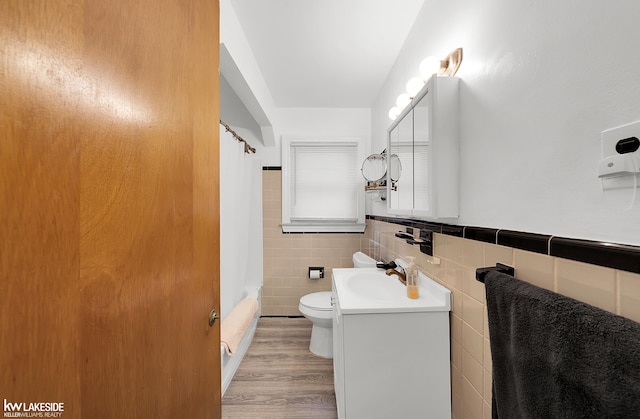 full bathroom with vanity, toilet, tile walls, hardwood / wood-style floors, and shower / tub combo with curtain