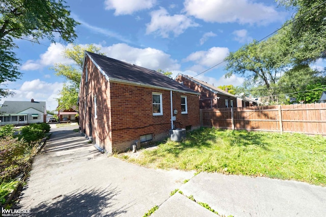 view of side of home with a lawn and central AC